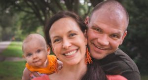 Kathryn Topham, Director of Clinical Services, headshot with her husband and baby.